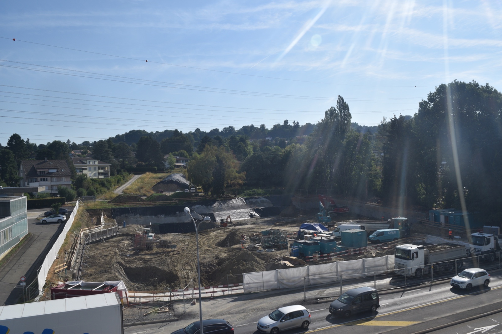 Photo brute d'un chantier, avec des véhicules en mouvement sur la route au premier plan
